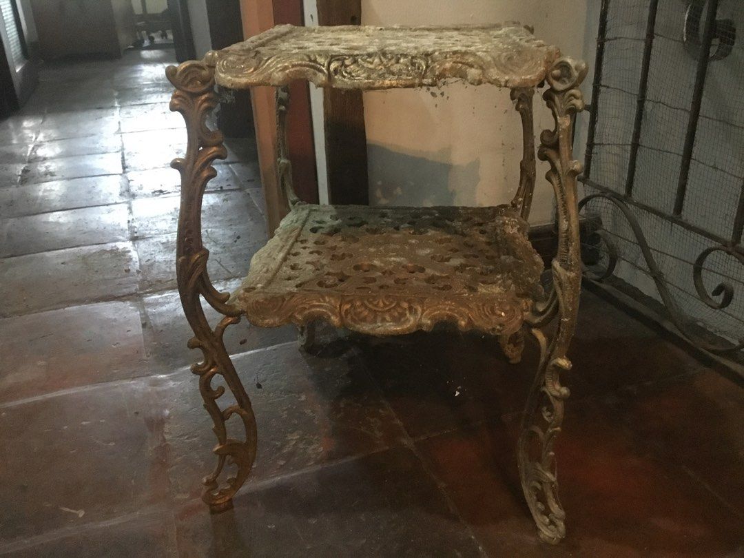 Ornate Cast Iron Two Tier Side Table Plant Stand (Category: Tables & Sets) located in Manila. Submitted by roberto.enriquez (Listing ID 1466967944, Image 3). Description: - Type: Two-tier metal stand / accent table - Material: Heavy cast iron with solid, sturdy structure - Design: Intricate scrollwork patterns, ornate curved legs, square tabletop, and matching lower shelf - Style: Classic antique French provincial or Victorian garden - Finish: Go