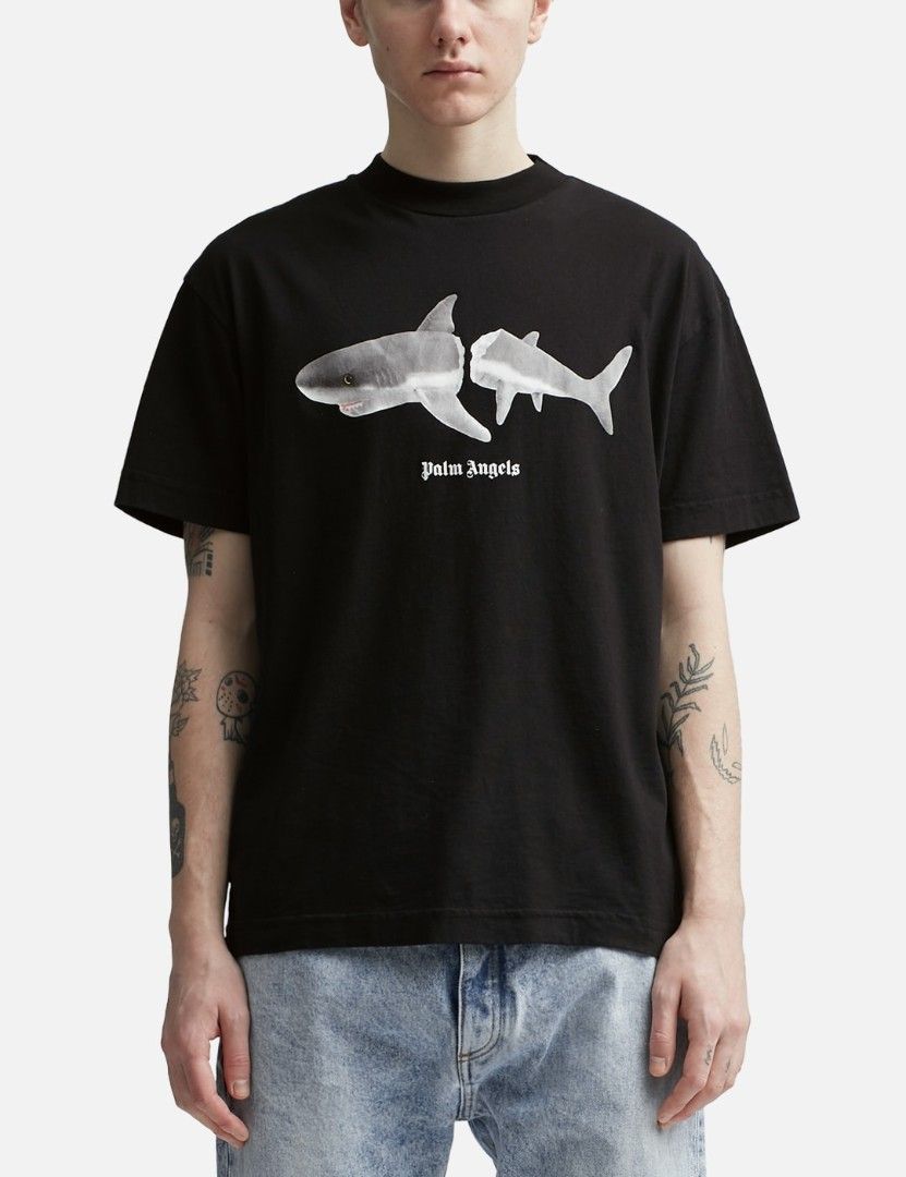 Palm Angels Shark Graphic Black Tee (Category: Tshirts & Polo Shirts ) located in San Francisco. Submitted by Intaw20 (Listing ID 1466935786, Image 2). Description: -Dimes 21 x 29 - Palm Angels black t-shirt -Authentication not Guaranteed - Split shark graphic with small white text logo on the chest - Large white gothic arched lettering printed across the back - Classic ribbed crew neck collar and short sleeves - Clean fabric with crisp, crack-fr