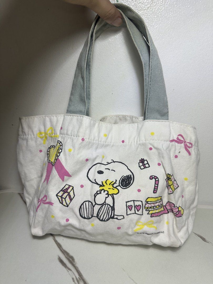 Peanuts Snoopy Canvas Mini Tote Bag Yellow Grey (Category: Tote Bags) located in Quezon City. Submitted by swift.thriftz (Listing ID 1466905093, Image 1). Description: - Authentic ©2012 Peanuts Worldwide LLC merchandise - Material: Durable white canvas with stylish grey fabric handles - Front Design: Snoopy surrounded by festive gifts and polka dots - Back Design: Woodstock in a heart-shaped hot air balloon with clouds and stars - Size: Mini/Smal