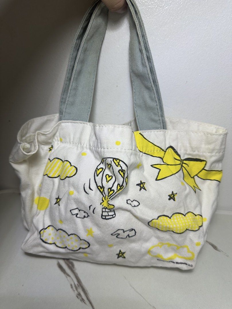 Peanuts Snoopy Canvas Mini Tote Bag Yellow Grey (Category: Tote Bags) located in Quezon City. Submitted by swift.thriftz (Listing ID 1466905093, Image 2). Description: - Authentic ©2012 Peanuts Worldwide LLC merchandise - Material: Durable white canvas with stylish grey fabric handles - Front Design: Snoopy surrounded by festive gifts and polka dots - Back Design: Woodstock in a heart-shaped hot air balloon with clouds and stars - Size: Mini/Smal