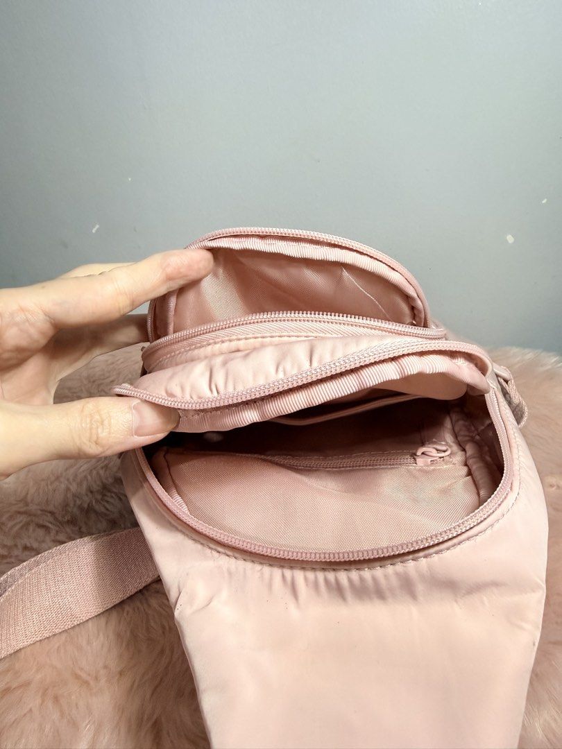 Pink Nylon Sling Bag Crossbody Backpack (Category: Cross-body Bags) located in Quezon City. Submitted by shaberbree (Listing ID 1466908246, Image 3). Description: - Color: Soft pink - Material: Durable nylon - Design: Multiple zippered compartments with an embroidered circular logo - Strap: Adjustable thick shoulder strap with side-release buckle - Interior: Clean lining with an extra zipper pocket - Style: Handy everyday crossbody bag for hands-