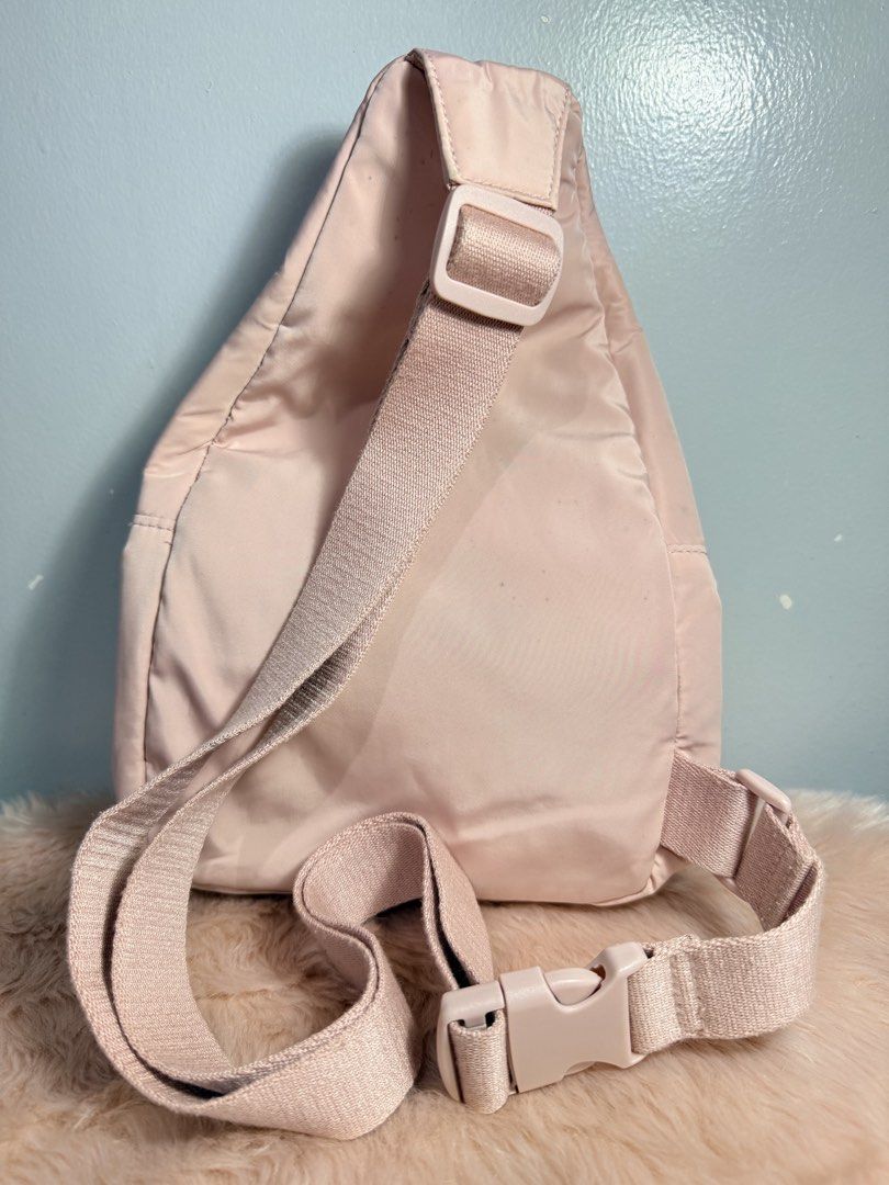 Pink Nylon Sling Bag Crossbody Backpack (Category: Cross-body Bags) located in Quezon City. Submitted by shaberbree (Listing ID 1466908246, Image 2). Description: - Color: Soft pink - Material: Durable nylon - Design: Multiple zippered compartments with an embroidered circular logo - Strap: Adjustable thick shoulder strap with side-release buckle - Interior: Clean lining with an extra zipper pocket - Style: Handy everyday crossbody bag for hands-