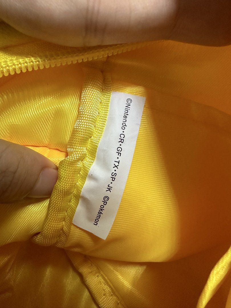 Pokémon Pikachu Plush Chara-Koro Bag (Category: Tote Bags) located in Quezon City. Submitted by swift.thriftz (Listing ID 1466884755, Image 3). Description: - Official Nintendo & Pokémon merchandise with copyright tag inside - Adorable bright yellow plush design featuring Pikachu's tail and back stripes - Soft fleece exterior texture for a cozy feel - Secure zipper closure on the main compartment - Convenient zippered front pocket for small essen