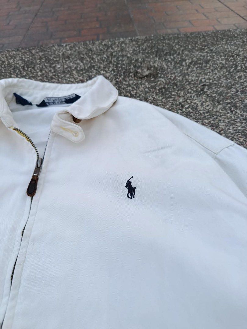 Polo by Ralph Lauren White Jacket (Category: Coats, Jackets and Outerwear) located in Manila. Submitted by luckyhorse.f804d6 (Listing ID 1466877613, Image 2). Description: - Brand: Polo by Ralph Lauren - Color: White with dark blue embroidered pony logo - Size: Medium (tag inside collar) - Material: 100% cotton (Made in Thailand) - Features: Full zip-up closure with leather pull, classic collar, front pockets, and elastic cuffs/hem - Condition: E