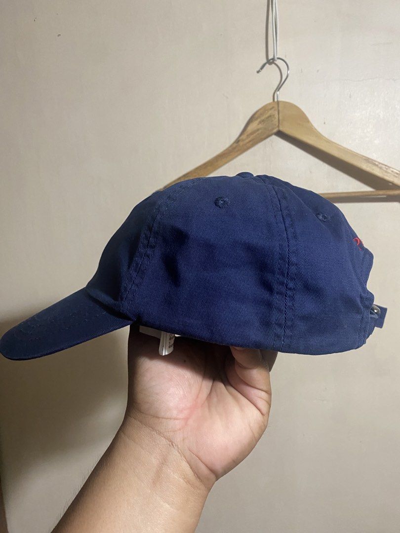 Polo Ralph Lauren Navy Blue Cap (Category: Caps & Hats) located in Bocaue. Submitted by pards23 (Listing ID 1466903768, Image 2). Description: - Brand: Polo Ralph Lauren - Color: Classic navy blue with red accents - Design: Red embroidered pony logo on the front and 'POLO' embroidery above the back strap - Material: Sturdy, structured cotton fabric - Fit: Fully adjustable strap with an embossed metal buckle - Condition: Clean and well-maintained 