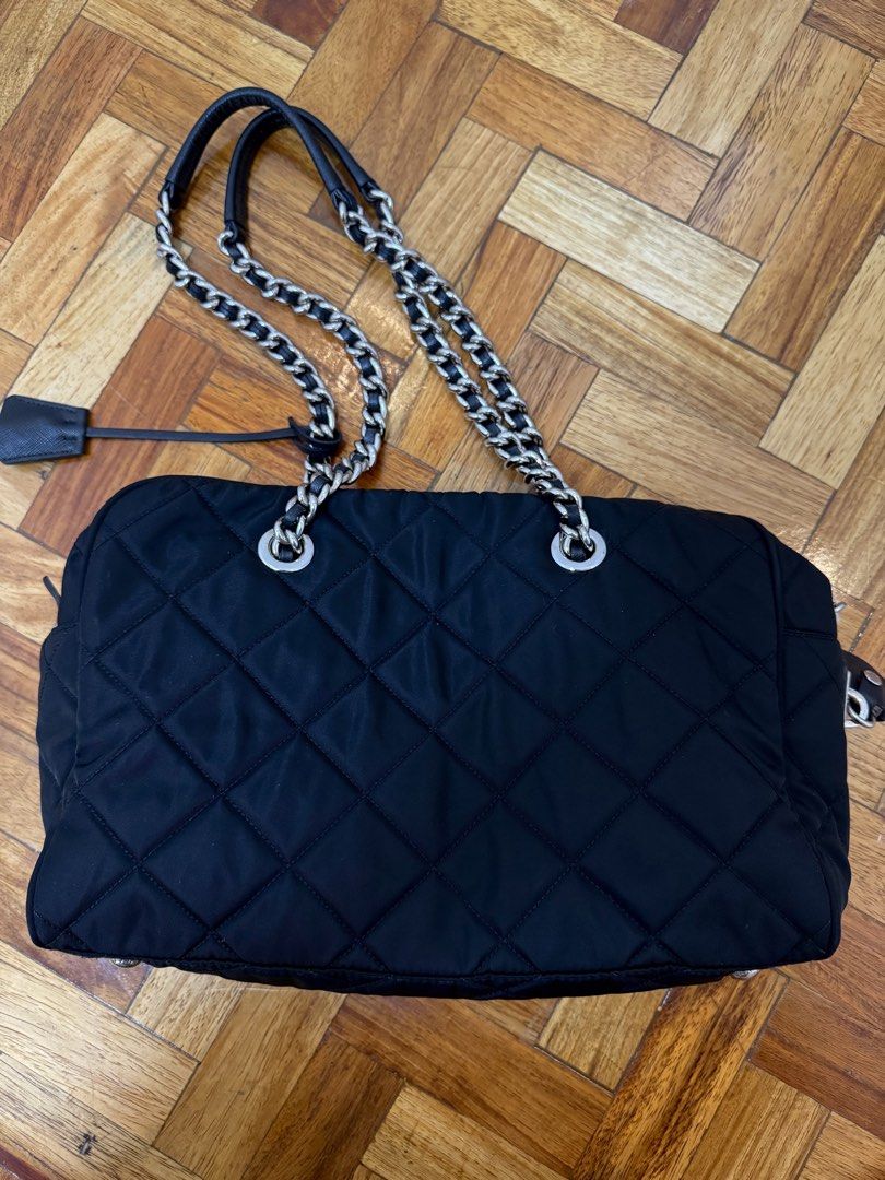 Prada Quilted Nylon Chain Shoulder Bag Black 1BB903 (Category: Luxury Bags & Wallets) located in Quezon City. Submitted by jfr22 (Listing ID 1466778357, Image 3). Description: - Authentic Prada shoulder bag in classic black quilted nylon - Silver chain straps with comfortable leather shoulder guards - Iconic Prada triangle logo plaque on the front - Secure top zipper closure with clean, sturdy hardware - Signature black nylon lining with Prada mo