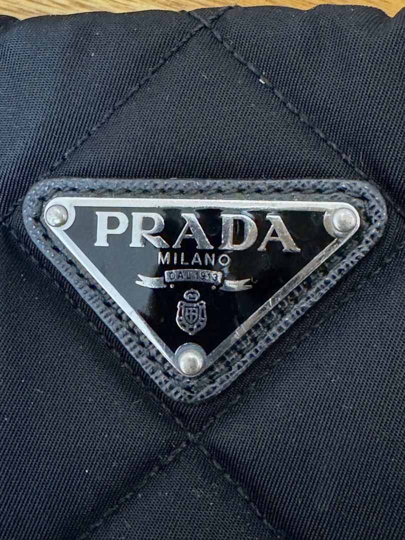 Prada Quilted Nylon Chain Shoulder Bag Black 1BB903 (Category: Luxury Bags & Wallets) located in Quezon City. Submitted by jfr22 (Listing ID 1466778357, Image 2). Description: - Authentic Prada shoulder bag in classic black quilted nylon - Silver chain straps with comfortable leather shoulder guards - Iconic Prada triangle logo plaque on the front - Secure top zipper closure with clean, sturdy hardware - Signature black nylon lining with Prada mo