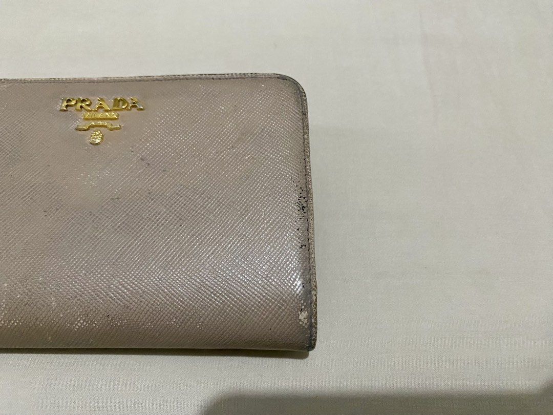Prada Saffiano Leather Bi-fold Wallet Beige (Category: Wallets & Card holders) located in Makati City. Submitted by purple101395 (Listing ID 1466884170, Image 3). Description: Signs of wear around the edges, corners, and flap closure. Button and zipper works well. No inclusions..