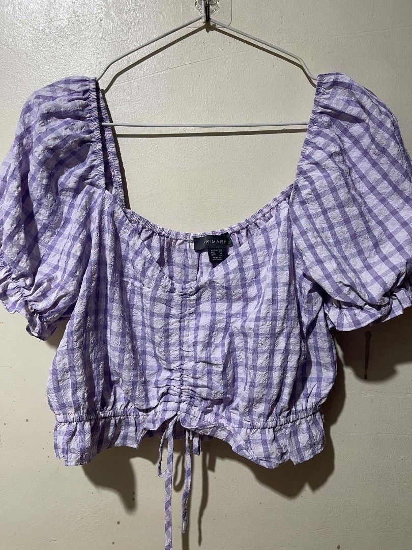 Primark Purple Gingham Crop Blouse UK 14 (Category: Blouses) located in Cebu City. Submitted by elon_888 (Listing ID 1466961519, Image 3). Description: - Brand: Primark - Size: UK 14 / EUR 42 / USA 10 - Color/Pattern: Purple and white gingham - Material: Textured seersucker fabric - Design: Square neckline, puff sleeves with ruffled cuffs, and center front ruching - Fit: Elasticated shoulders and back neckline with a tie drawstring hem.
