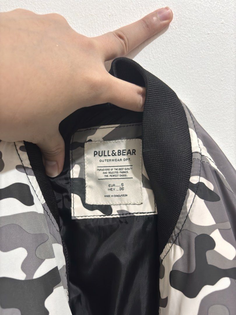Pull & Bear Camouflage Bomber Jacket Size S (Category: Coats, Jackets and Outerwear) located in Manila. Submitted by char_69 (Listing ID 1466912922, Image 3). Description: - Brand: Pull & Bear - Design: Black, grey, and white camouflage print - Size: S (EUR S, MEX 36) - Features: Zip-up front, sleeve utility pocket, smooth black lining, and black ribbed collar, cuffs, and hem - Origin: Made in Bangladesh - Condition: Clean and well maintained - S