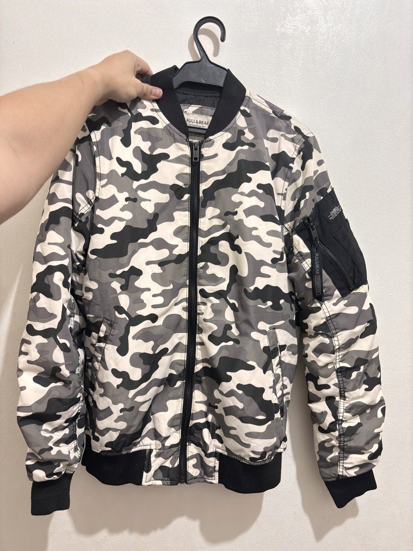 Pull & Bear Camouflage Bomber Jacket Size S (Category: Coats, Jackets and Outerwear) located in Manila. Submitted by char_69 (Listing ID 1466912922, Image 1). Description: - Brand: Pull & Bear - Design: Black, grey, and white camouflage print - Size: S (EUR S, MEX 36) - Features: Zip-up front, sleeve utility pocket, smooth black lining, and black ribbed collar, cuffs, and hem - Origin: Made in Bangladesh - Condition: Clean and well maintained - S