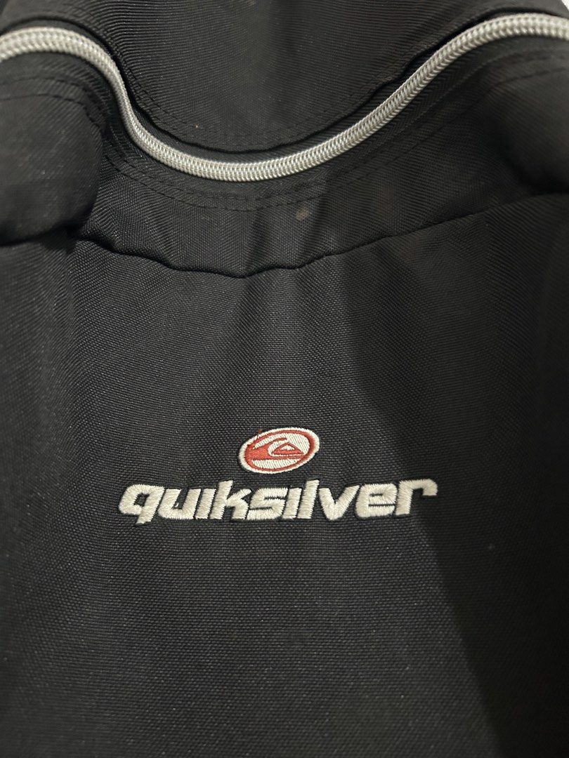 Quiksilver Black Backpack with Grey Straps (Category: Backpacks) located in Angeles City. Submitted by cassey_phoenix (Listing ID 1466882084, Image 2). Description: - Brand: Quiksilver - Color: Black with grey straps and zipper details - Logo: Embroidered front logo and red side tag - Compartments: Main compartment and front zippered pocket - Features: Adjustable shoulder straps and top hanging loop - Material: Durable fabric construction - Condi