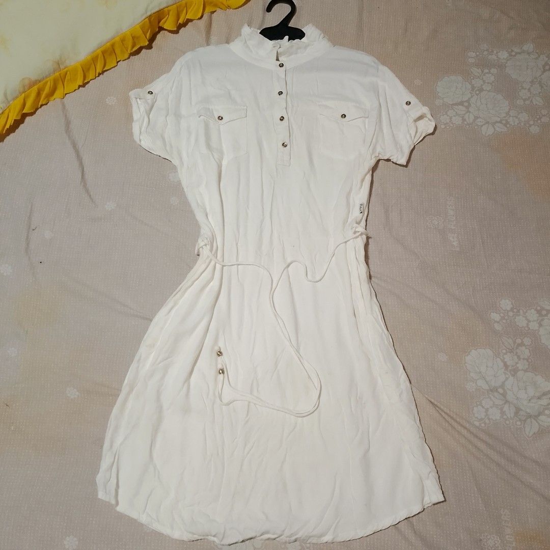 REDGIRL White Collared Dress (Category: Dresses) located in Pandi. Submitted by lorichuu (Listing ID 1466868442, Image 1). Description: For Sale: Redgirl White Collared Dress Size: Medium (M) Brand: Redgirl - Pre-loved and still wearable - Classic white design with gold-tone buttons and adjustable waist tie - Features two front pockets and a collared neckline - Has visible signs of use and some stains - Has small holes — please manage expectation