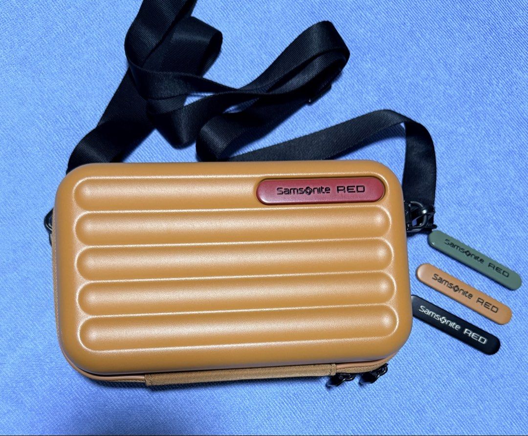 Samsonite RED hard shell crossbody bag tan (Category: Cross-body Bags) located in Dasmarinas. Submitted by toyang50 (Listing ID 1466780567, Image 1). Description: Samsonite RED hard shell crossbody bag in a tan colorway. Ridged hard exterior design paired with a red logo badge. Adjustable black shoulder strap included. Interior lined with yellow fabric, featuring mesh pockets and compartments for organization. Three interchangeable color tags in 