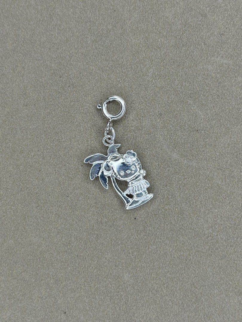 Sanrio Hello Kitty 2006 Hula Palm Tree 925 Silver Charm (Category: Charms) located in Bulacan. Submitted by vintagetreasureby.mivida (Listing ID 1466957908, Image 1). Description: - Authentic 2006 Sanrio Kitty hula charm - Crafted from solid sterling silver (stamped 925) - Features a cute tropical design with Kitty and a palm tree - Official Sanrio copyright text on the back - Equipped with a spring ring clasp for easy clipping onto bracelets or 