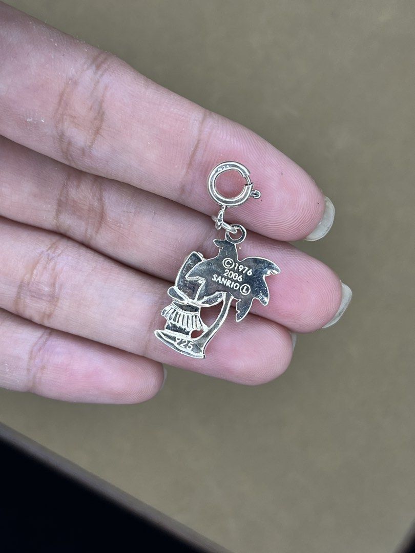 Sanrio Hello Kitty 2006 Hula Palm Tree 925 Silver Charm (Category: Charms) located in Bulacan. Submitted by vintagetreasureby.mivida (Listing ID 1466957908, Image 3). Description: - Authentic 2006 Sanrio Kitty hula charm - Crafted from solid sterling silver (stamped 925) - Features a cute tropical design with Kitty and a palm tree - Official Sanrio copyright text on the back - Equipped with a spring ring clasp for easy clipping onto bracelets or 