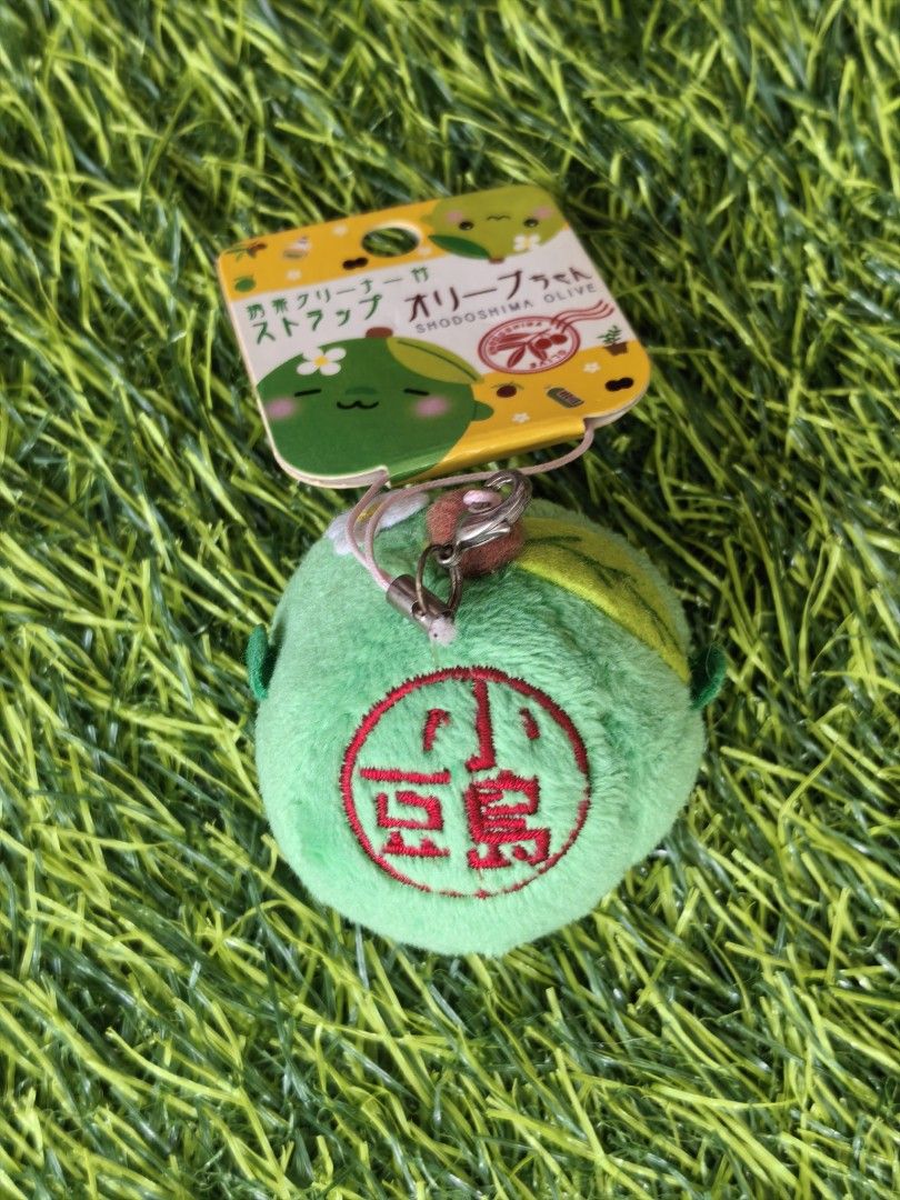 Shodoshima Olive Chan Plush Strap (Category: Plushies & Soft Toys) located in Paranaque City. Submitted by furugiyafinds (Listing ID 1466860444, Image 2). Description: - Authentic Shodoshima green olive character plush strap - Made from ultra-soft fuzzy material with an adorable embroidered face, pink cheeks, and a tiny white flower - Back features unique red Japanese text embroidery inside a circle - Includes original attached paper tag - Equipp
