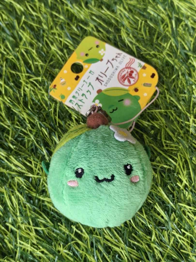 Shodoshima Olive Chan Plush Strap (Category: Plushies & Soft Toys) located in Paranaque City. Submitted by furugiyafinds (Listing ID 1466860444, Image 1). Description: - Authentic Shodoshima green olive character plush strap - Made from ultra-soft fuzzy material with an adorable embroidered face, pink cheeks, and a tiny white flower - Back features unique red Japanese text embroidery inside a circle - Includes original attached paper tag - Equipp