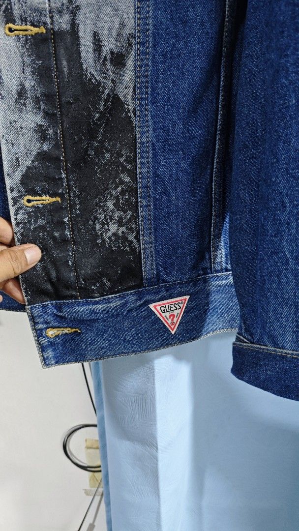 Stereo Vinyls x Guess Denim Jacket Size L (Category: Coats, Jackets and Outerwear) located in Davao. Submitted by jhinkertzp55934 (Listing ID 1466907661, Image 3). Description: - Brand: Stereo Vinyls x Guess - Item: Collaborative Denim Jacket - Color: Blue - Size: L dimes 25x28 - Material: Heavy denim fabric - Details: Graphic print portrait panels on front and placket, classic button-up front, contrast yellow stitching, chest pockets, and signat