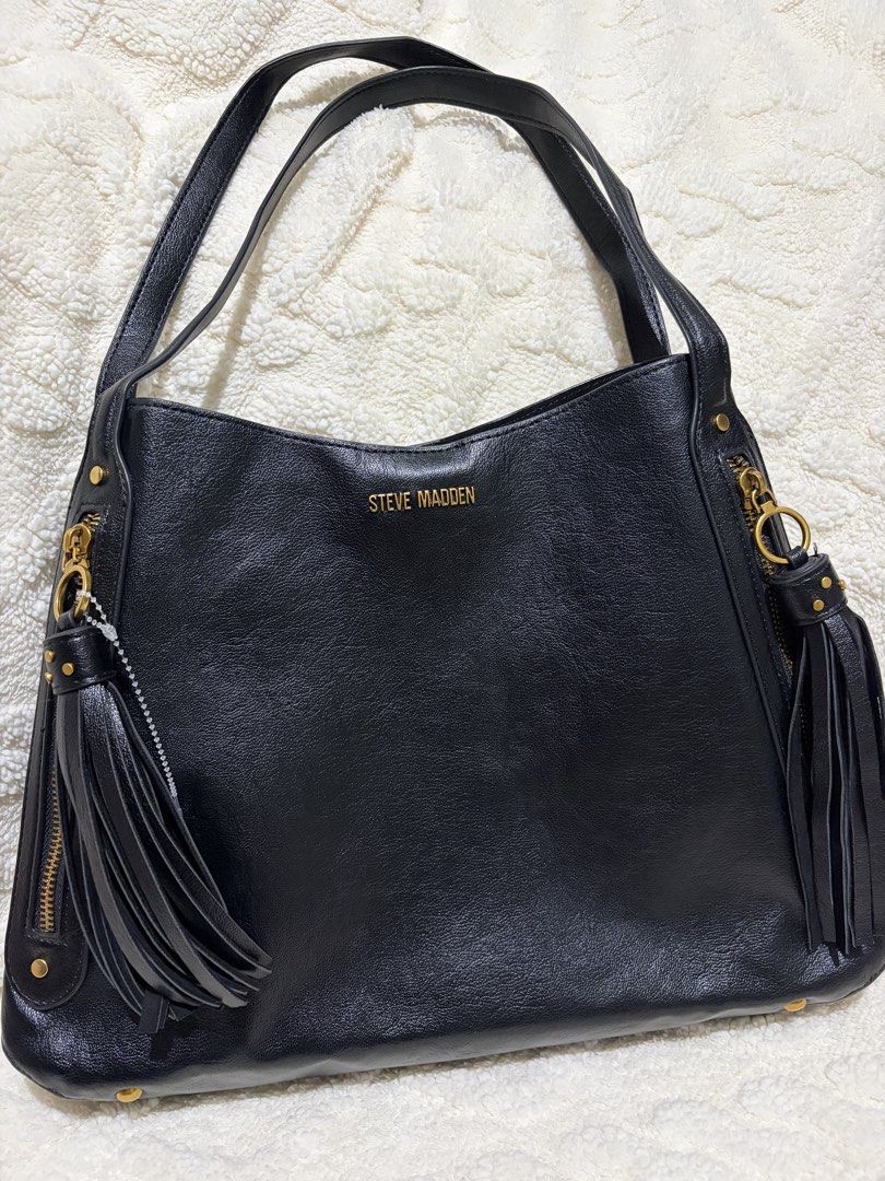 Steve Madden Black Shoulder Bag with Tassels (Category: Shoulder Bags) located in Paranaque City. Submitted by greatfinds108 (Listing ID 1466832434, Image 1). Description: - Brand: Steve Madden - Color: Black with luxury gold-tone hardware - Material: Durable faux leather - Design: Structured base with protective metal feet - Straps: Convenient double shoulder straps - Compartments: 2 side zipper pockets design with stylish tassel pulls, plus a m