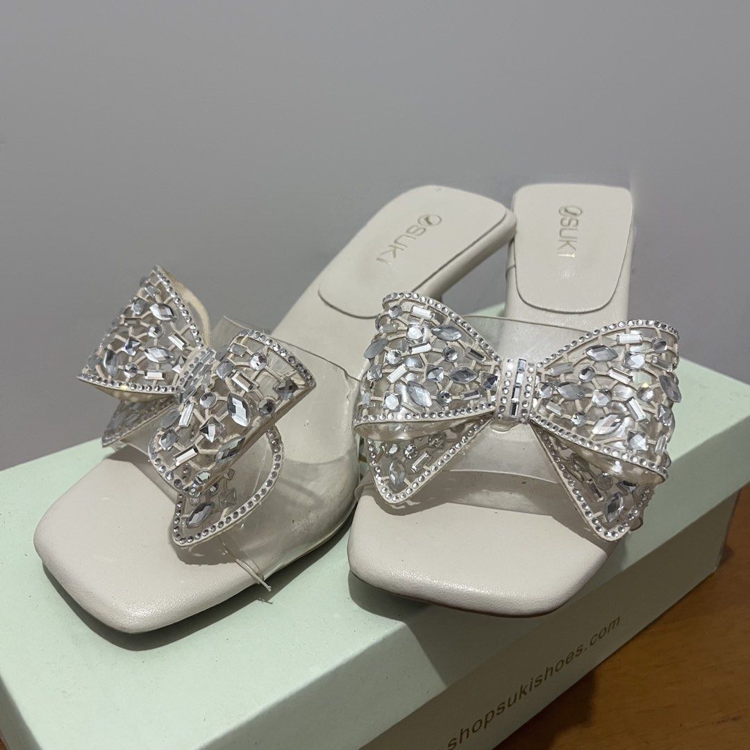 Suki Bone Rhinestone Bow Heels Size 35 (Category: Heels) located in Taguig. Submitted by 152hertz (Listing ID 1466857302, Image 1). Description: - Brand: Suki - Color: Bone (Off-White) - Size: 35 - Details: Clear strap with a large rhinestone bow, square toe, and stylish flare heel - Condition: Excellent, original box included - Source: Purchased directly from SM Store.