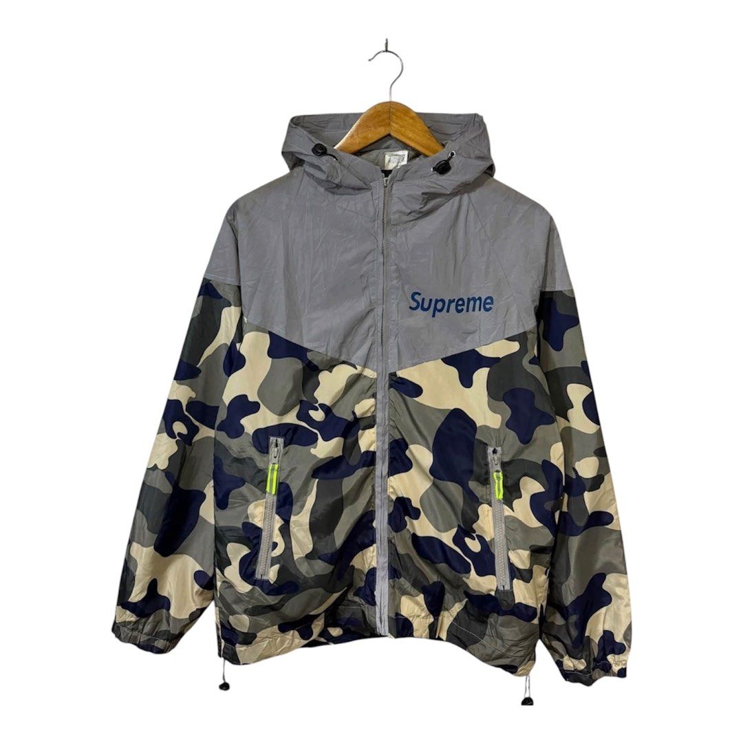 Supreme Camo Windbreaker Jacket Grey Blue Size M (Category: Coats, Jackets and Outerwear) located in Baguio. Submitted by gab_thrift (Listing ID 1466808412, Image 1). Description: - Brand: Supreme - Style: Windbreaker jacket - Colorway: Grey and camo with blue branding - Size: Medium (Made in USA) - Features: Full zip closure, adjustable hood drawstrings, and two zippered hand pockets - Branding: Blue Supreme text printed on the front chest and u