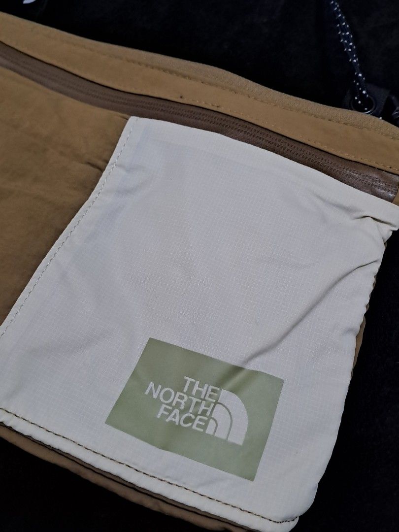 The North Face Crossbody Bag (Category: Cross-body Bags) located in Puerto Princesa. Submitted by jercksthriftph (Listing ID 1466966345, Image 2). Description: - Brand: The North Face - Colorway: Tan and off-white - Design: Front pocket with square TNF logo patch and orange zipper pull tab detail - Compartment: Secure zip-closed main compartment - Interior: Unique topographic map pattern lining with a built-in mesh divider pocket - Strap: Adjusta