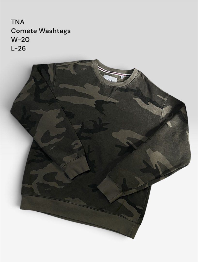 Tna Camo Sweatshirt (Category: Coats, Jackets and Outerwear) located in Andop. Submitted by zealtree_09ac54 (Listing ID 1466946646, Image 1). Description: - Brand: Tna - Design: Green camouflage print, classic crewneck - Interior: Soft fleece lining for extra warmth - Details: Ribbed cuffs and hem - Measurements: Width 20" | Length 26" - Condition: Excellent, perfect for easy everyday layering.