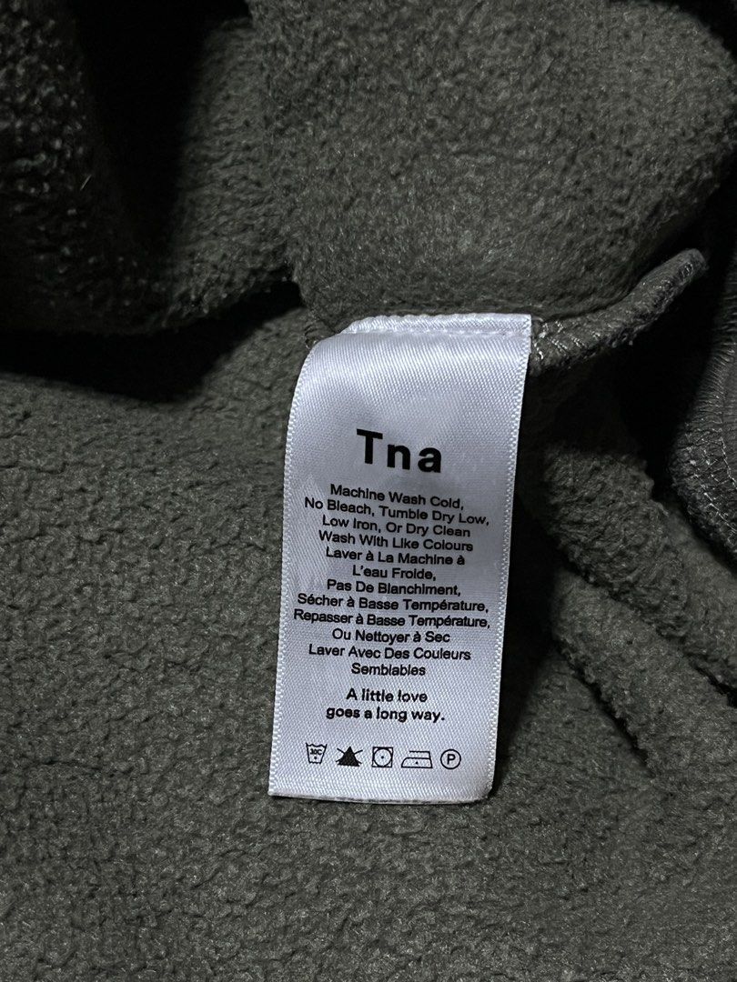 Tna Camo Sweatshirt (Category: Coats, Jackets and Outerwear) located in Andop. Submitted by zealtree_09ac54 (Listing ID 1466946646, Image 2). Description: - Brand: Tna - Design: Green camouflage print, classic crewneck - Interior: Soft fleece lining for extra warmth - Details: Ribbed cuffs and hem - Measurements: Width 20" | Length 26" - Condition: Excellent, perfect for easy everyday layering.