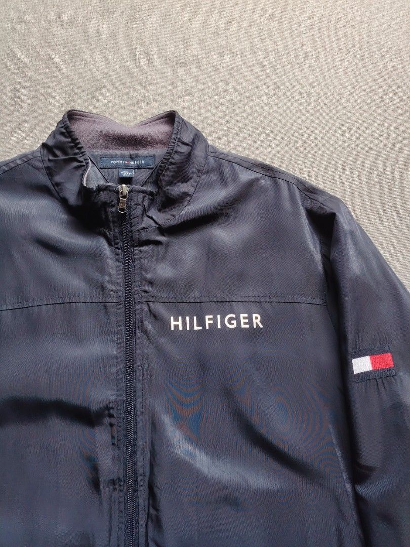 Tommy Hilfiger Navy Blue Zip Up Jacket (Category: Coats, Jackets and Outerwear) located in Taguig. Submitted by _theroom.ph (Listing ID 1466840902, Image 2). Description: - Brand: Tommy Hilfiger - Color: Navy Blue - Size: XXL - Design: Bold HILFIGER chest print & classic flag logo on left sleeve - Comfort: Fleece-lined stand-up collar, ribbed cuffs, and hem - Features: Full zip closure with custom hardware, two front welt pockets - Origin: Made i