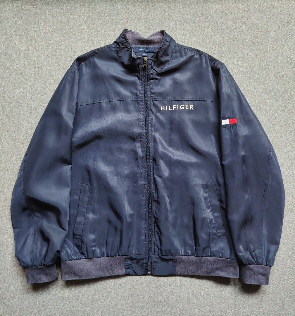 Tommy Hilfiger Navy Blue Zip Up Jacket (Category: Coats, Jackets and Outerwear) located in Taguig. Submitted by _theroom.ph (Listing ID 1466840902, Image 1). Description: - Brand: Tommy Hilfiger - Color: Navy Blue - Size: XXL - Design: Bold HILFIGER chest print & classic flag logo on left sleeve - Comfort: Fleece-lined stand-up collar, ribbed cuffs, and hem - Features: Full zip closure with custom hardware, two front welt pockets - Origin: Made i