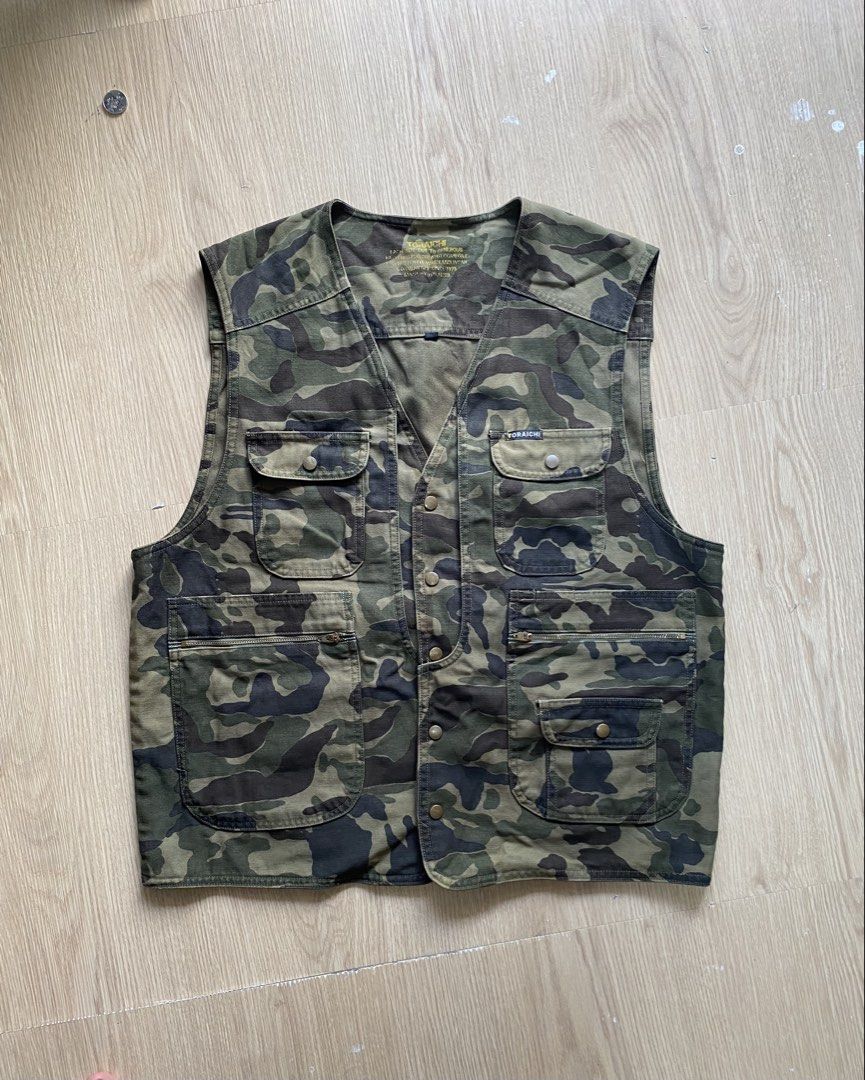 Toraichi 1990s Camo Utility Vest (Category: Coats, Jackets and Outerwear) located in Zamboanga. Submitted by ak.hunt (Listing ID 1466788181, Image 1). Description: Toraichi Co., Ltd., established in Okayama, is revered in Japan as the premier purveyor of traditional tobi-shoku workwear and rugged construction attire. This utility vest exemplifies their practical heritage, featuring a robust cotton-blend twill chassis dressed in a classic woodland