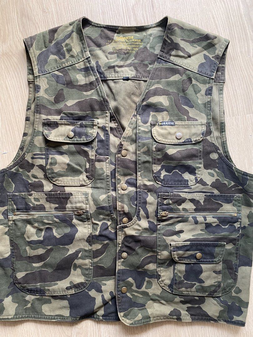 Toraichi 1990s Camo Utility Vest (Category: Coats, Jackets and Outerwear) located in Zamboanga. Submitted by ak.hunt (Listing ID 1466788181, Image 3). Description: Toraichi Co., Ltd., established in Okayama, is revered in Japan as the premier purveyor of traditional tobi-shoku workwear and rugged construction attire. This utility vest exemplifies their practical heritage, featuring a robust cotton-blend twill chassis dressed in a classic woodland