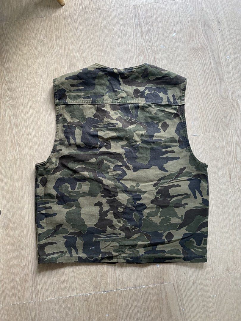 Toraichi 1990s Camo Utility Vest (Category: Coats, Jackets and Outerwear) located in Zamboanga. Submitted by ak.hunt (Listing ID 1466788181, Image 2). Description: Toraichi Co., Ltd., established in Okayama, is revered in Japan as the premier purveyor of traditional tobi-shoku workwear and rugged construction attire. This utility vest exemplifies their practical heritage, featuring a robust cotton-blend twill chassis dressed in a classic woodland