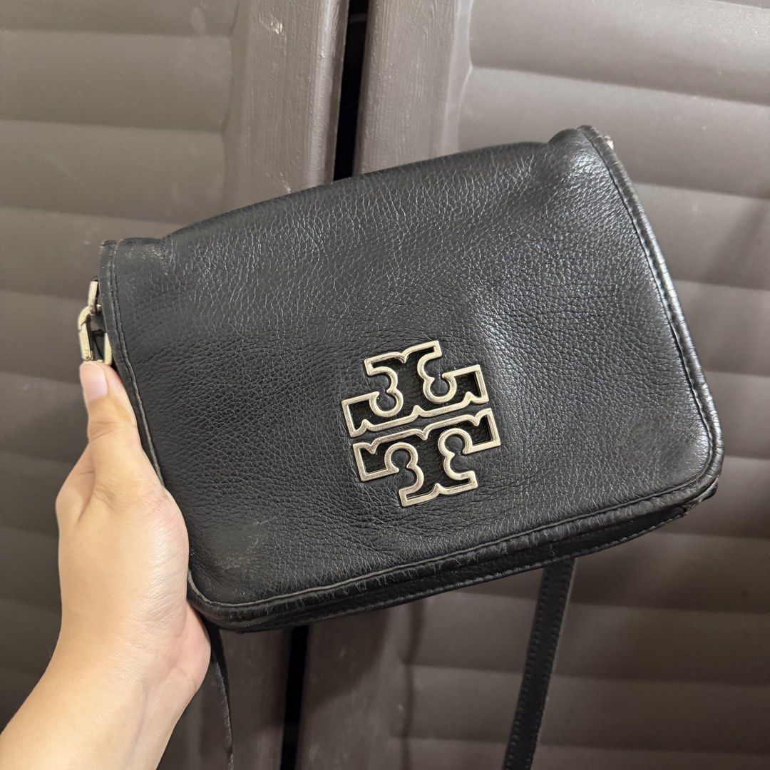Tory Burch Black Leather Crossbody Bag (Category: Luxury Bags & Wallets) located in Rizal. Submitted by lovegclothingph (Listing ID 1466909915, Image 1). Description: Black pebbled leather crossbody bag from Tory Burch. Silver-tone hardware and prominent logo plaque on the front flap closure. Structured rectangular shape with side chain link strap detail and zippered inner pocket. Grainy leather texture throughout with minor wear along the edges 