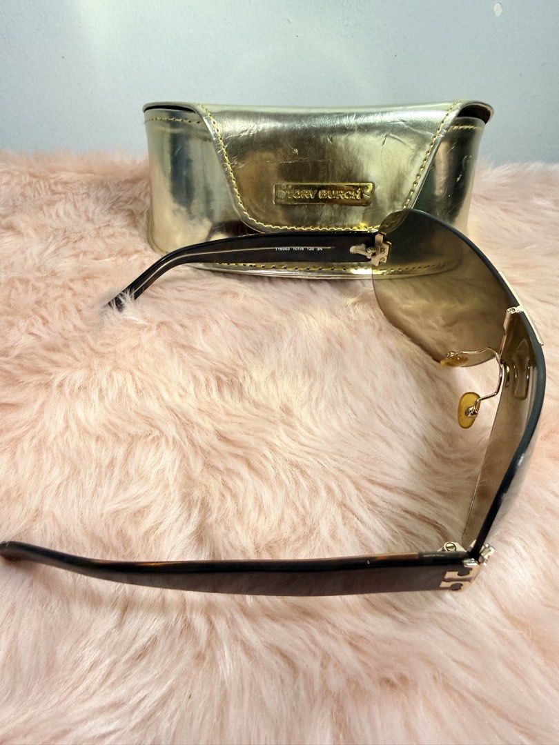 Tory Burch Shield Sunglasses with Gold Case (Category: Sunglasses & Eyewear) located in Quezon City. Submitted by shaberbree (Listing ID 1466908671, Image 3). Description: - Brand: Tory Burch - Style: Shield sunglasses with gradient brown tint - Frame: Dark tortoiseshell arms with gold Tory Burch logo hardware at hinges - Model No: TY6003 101/8 120 3N - Inclusion: Matching metallic gold hard case with embossed Tory Burch plaque - Condition: Well-