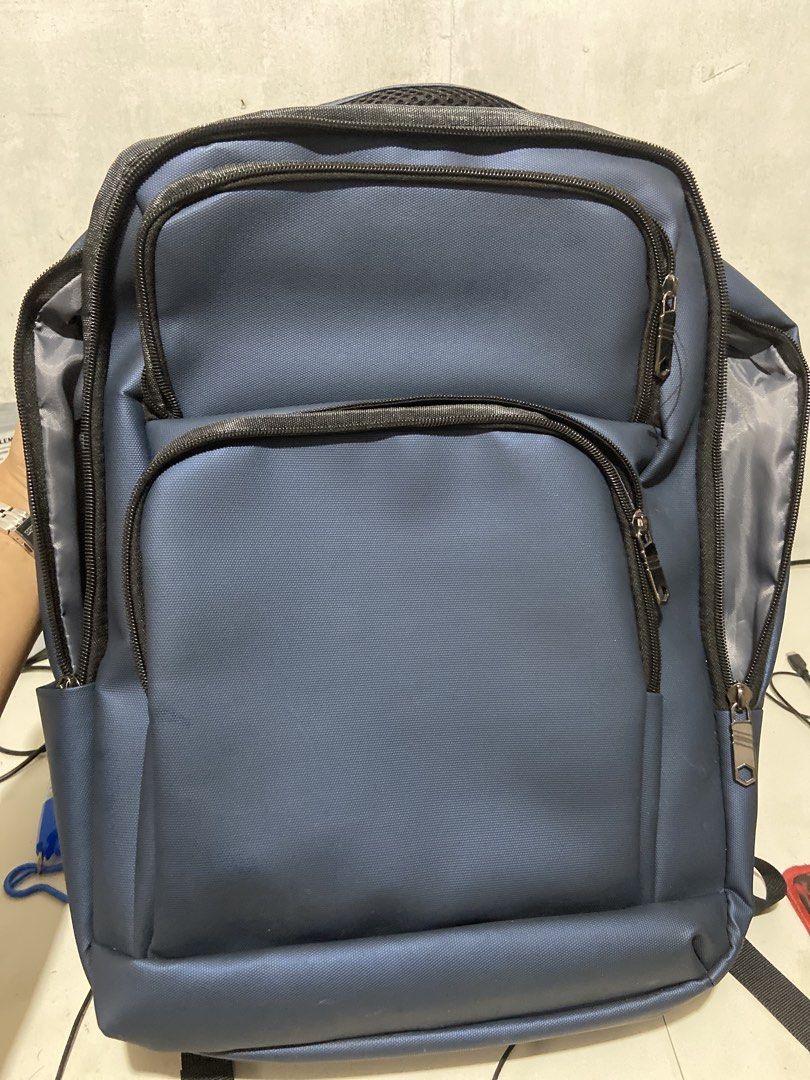 Travel Basics Blue Laptop Backpack with Multiple Zipped Compartments (Category: Backpacks) located in Makati City. Submitted by consbuenaventura (Listing ID 1466809696, Image 1). Description: - Color: Blue with grey interior lining - Storage: Multi-compartment design with several front zipped pockets for easy organization - Laptop Storage: Dedicated internal laptop sleeve with a secure strap and red laptop icon - Durability: Sturdy top handle for
