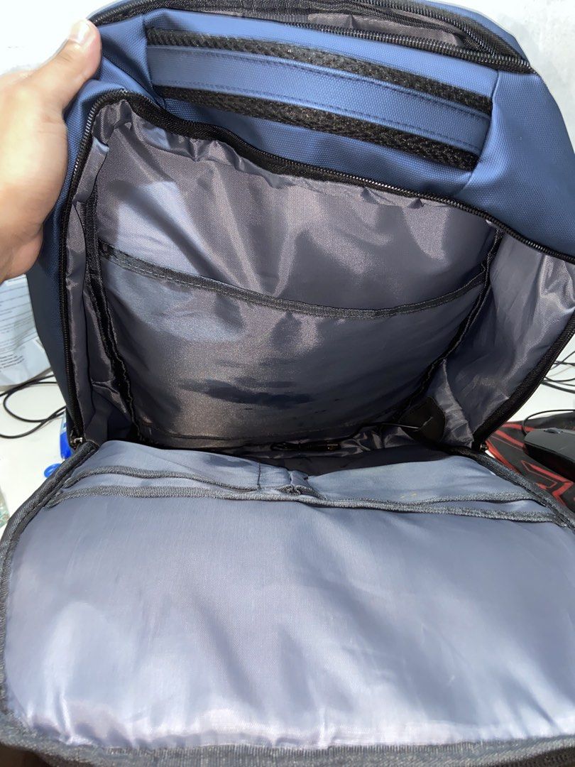 Travel Basics Blue Laptop Backpack with Multiple Zipped Compartments (Category: Backpacks) located in Makati City. Submitted by consbuenaventura (Listing ID 1466809696, Image 2). Description: - Color: Blue with grey interior lining - Storage: Multi-compartment design with several front zipped pockets for easy organization - Laptop Storage: Dedicated internal laptop sleeve with a secure strap and red laptop icon - Durability: Sturdy top handle for