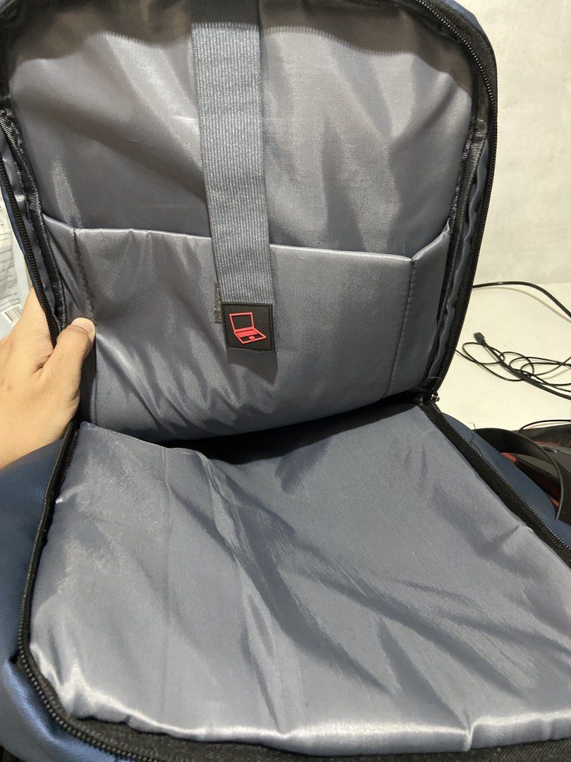 Travel Basics Blue Laptop Backpack with Multiple Zipped Compartments (Category: Backpacks) located in Makati City. Submitted by consbuenaventura (Listing ID 1466809696, Image 3). Description: - Color: Blue with grey interior lining - Storage: Multi-compartment design with several front zipped pockets for easy organization - Laptop Storage: Dedicated internal laptop sleeve with a secure strap and red laptop icon - Durability: Sturdy top handle for