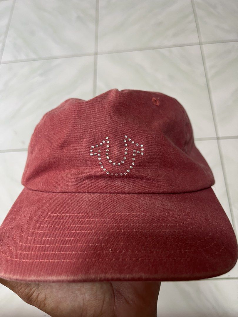 True Religion Red Rhinestone Logo Cap (Category: Caps & Hats) located in Naga. Submitted by stoob.finds (Listing ID 1466800431, Image 1). Description: - Brand: True Religion - Color: Red with vintage wash look - Design: Eye-catching rhinestone horseshoe logo on the front - Material: 100% cotton for comfort - Closure: Fully adjustable plastic snapback - Condition: Clean inside and out with original brand tags.