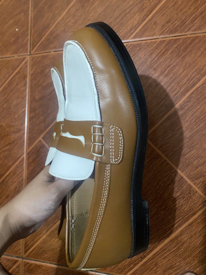 Two-tone brown and white penny loafers (Category: Casual Shoes) located in Manila. Submitted by trish.may1 (Listing ID 1466823036, Image 2). Description: - Style: Two-tone brown and white penny loafers (slip-on) - Design: White toe panels with brown leather accents and white contrast stitching - Heel: Black stacked heel - Soles: Sturdy outer soles with plenty of life left - Condition: Inner soles show wear and peeling on the lining.