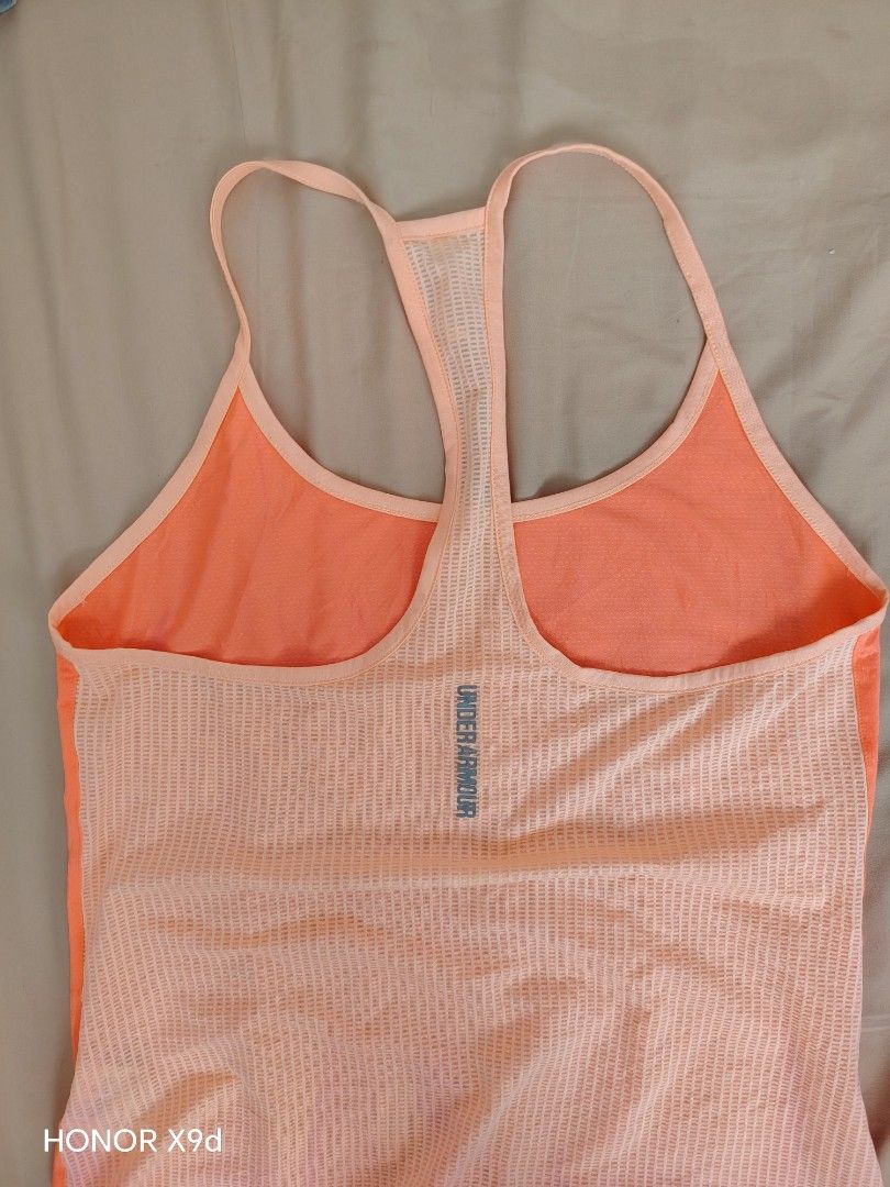 Under Armour Orange Athletic Tank Top Racerback (Category: Activewear) located in Mabalacat. Submitted by Jackikay.PreLoved (Listing ID 1466857578, Image 2). Description: - Brand: Under Armour - Type: Racerback tank top - Color: Bright orange - Features: Super lightweight, Breathable mesh paneling down the back and sides - Details: Reflective UA logo near the bottom hem and spine - Ideal for: Running, workouts, and the gym.