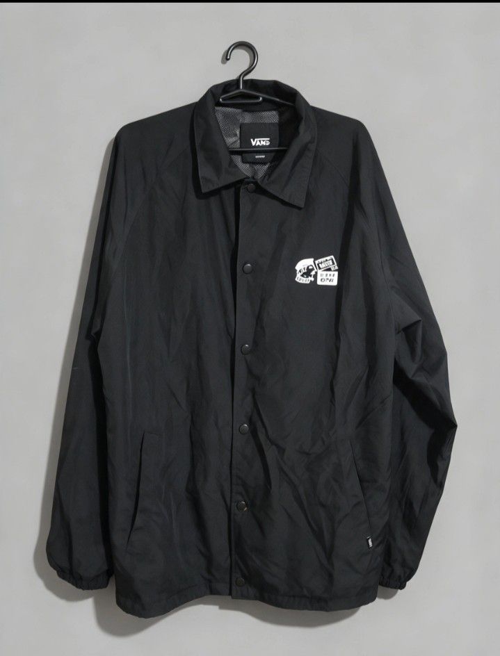 Vans Black Coach Jacket Off The Wall (Category: Coats, Jackets and Outerwear) located in Sorsogon. Submitted by tanggoal (Listing ID 1466797624, Image 1). Description: - Brand: Vans - 1,5k, Free shipping✅ - issue sa last picture📌 - Style: Black coach jacket with snap button closure and collared neckline - Design: Graphic print on left chest; large back illustration with clapperboard, 'Off The Wall' branding, and 'Tell A Friend About Vans' text -
