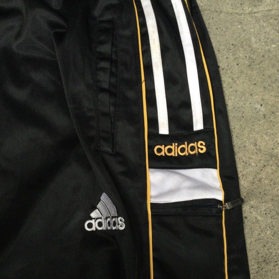 Vintage Bootleg Adidas Track Pants (Category: Joggers) located in Binangonan. Submitted by ininnep (Listing ID 1466925977, Image 2). Description: ✅ Item Identified: Vintage Adidas Classic 3-Stripes Track Pants 🏃‍♂️ Brand: Adidas —with embroidered trefoil logo, branded text,engraved zipper Size -32 to 40 Style Details: • Colorway: Black base with iconic white 3-Stripes + gold/yellow piping • Features: Elastic waistband, side hand pockets, zippere