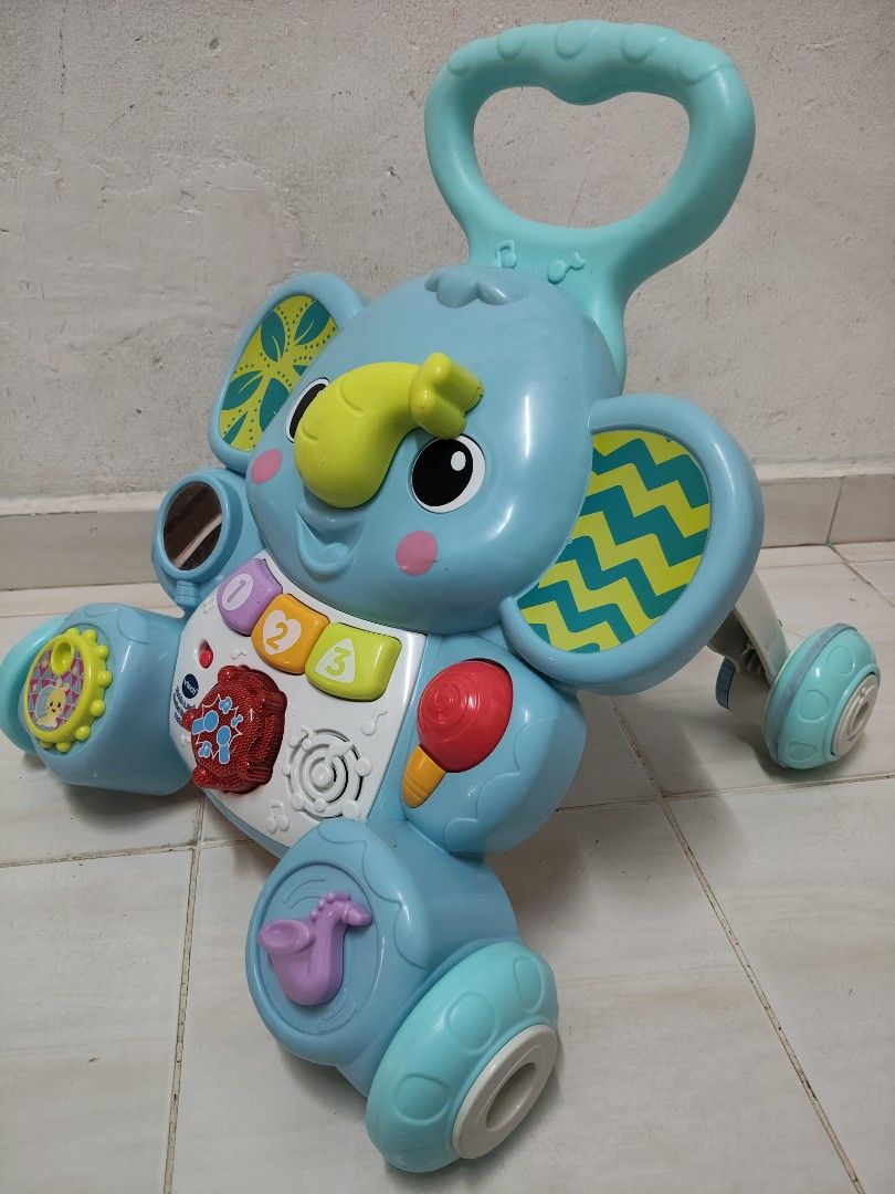 VTECH PUSH WALKER (Category: Infant Playtime) located in Hulu Selangor. Submitted by akmariana (Listing ID 1466803347, Image 2). Description: - Brand: VTech Bright Blue Elephant Walker - Interactive play panel: numbered buttons, light-up spinner, rattle, and saxophone toy - Safe mobility: Four sturdy wheels with textured rubber rings for secure rolling - Support: Sturdy arched frame designed to help babies take early walking steps - Features fun 