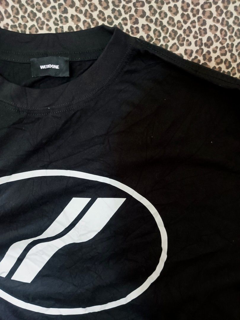 We11done Black Logo T-Shirt Size M (Category: Tshirts & Polo Shirts ) located in Davao. Submitted by jasondagam14678 (Listing ID 1466784696, Image 2). Description: - Brand: We11done - Color: Black - Size: Medium - Design: Large oval chest graphic logo with smaller cursive branding on the upper back - Details: Classic crew neck, short sleeves, woven inner collar tag, and interior care label - Material: Premium cotton - Condition: Excellent, well-m