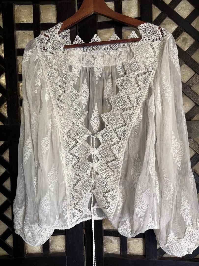 White Lace Trimmed Sheer Blouse (Category: Blouses) located in Batangas. Submitted by purple_and_orange (Listing ID 1460963711, Image 1). Description: - Sheer white blouse - V-neck with tie-up front - Long balloon sleeves - Intricate lace detailing on neckline and cuffs - Subtle embroidered pattern throughout fabric - Ideal for layering or a bohemian style.