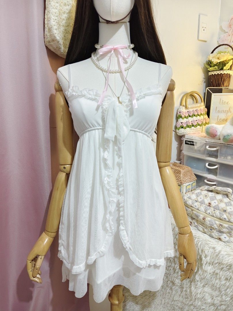 White Ruffled Camisole Mini Dress (Category: Dresses) located in Manila. Submitted by chynii_28 (Listing ID 1466865508, Image 3). Description: - Size: XS to SM - Color: Clean white - Design: Sweet ruffle trim along neckline and front opening with a tie detail - Detail: Layered sheer mesh skirt overlay - Condition: Excellent, no flaws found.