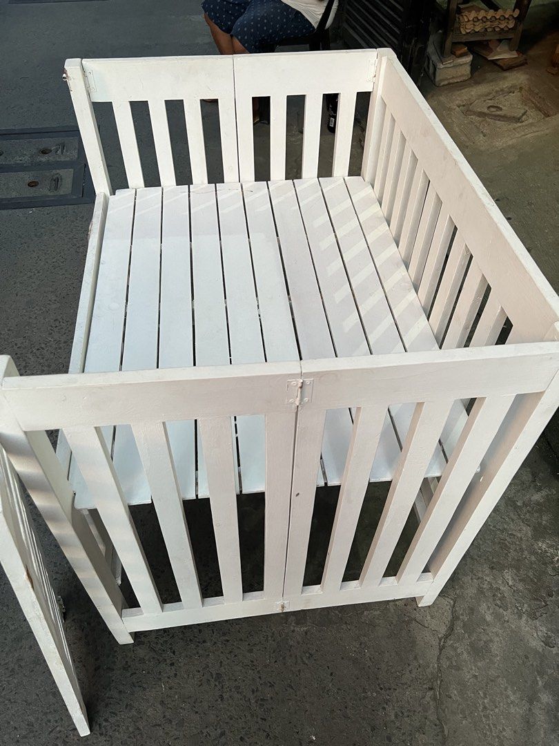 White Wooden Crib (Category: Cots & Cribs) located in Las Pinas. Submitted by seyswift (Listing ID 1466888838, Image 3). Description: - White painted wooden crib with a stylish slatted design - Built with convenient panels and a drop-down front gate for easy access - metal hinges need fixing - Pickup only due to size.