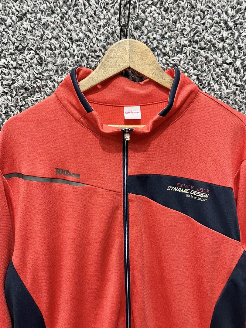 Wilson Sport "Dynamic Design" Full-Zip Track Jacket. | Size XL (Category: Coats, Jackets and Outerwear) located in General Trias. Submitted by zrchustle.604 (Listing ID 1466970478, Image 3). Description: Wilson Sport "Dynamic Design" Full-Zip Track Jacket. This functional training zip-up features a red body accented with dark navy/black geometric side paneling and chest overlays, complete with the text "Since 1914 Dynamic Design Wilson Sport" on 